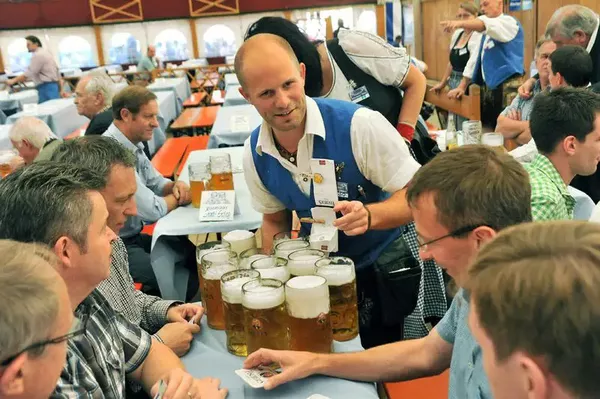 Bedienung bringt Maßkrüge an Biertisch