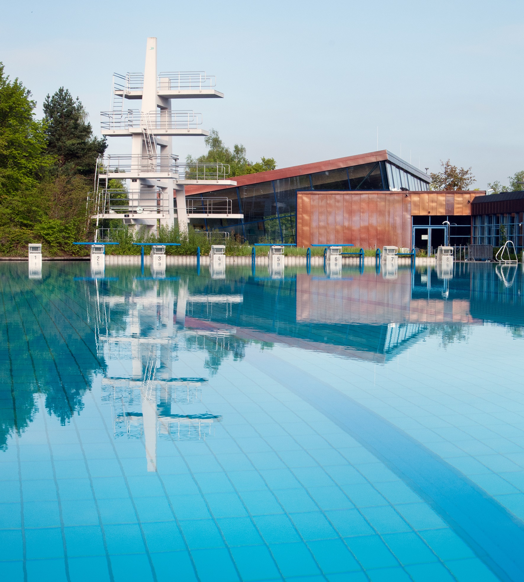 Schwimmerbecken des Freibads, dahinter der Sprungturm