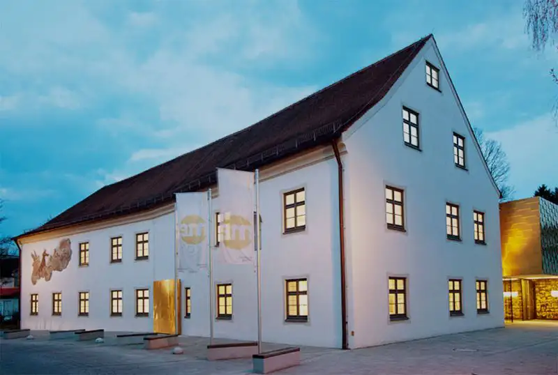 Nachtaufnahme des Museums Erding mit hell erleuchteten Fenstern